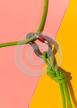 carabiner with a rope lies on a colored background. Equipment for climbing and mountaineering. reliable connection. Safety rope.