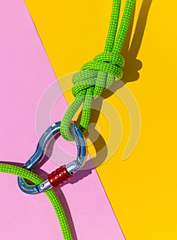 carabiner with a rope lies on a colored background. Equipment for climbing and mountaineering. reliable connection. Safety rope.