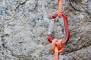 Carabiner with rope on rocky background