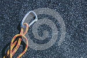 Carabiner on a texured roofing felt surface with many small grey stones