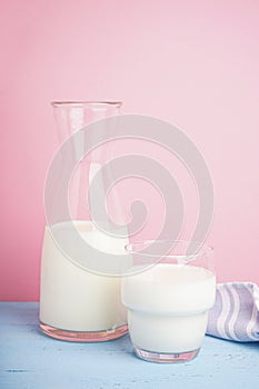 Carafe and glass of fresh milk on light blue wooden background