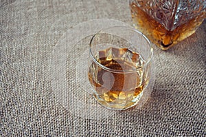 Carafe and glass of whisky, whiskey bourbon on a burlap, sacks background