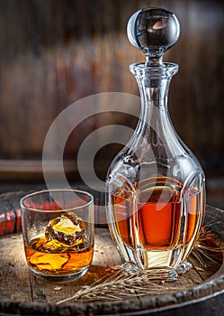 Carafe of whisky and glass of whisky on old wooden cask at the dark background