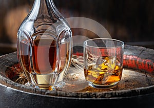 Carafe of whisky and glass of whisky on old wooden cask at the dark background