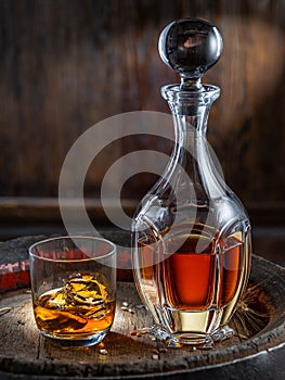 Carafe of whisky and glass of whisky on old wooden cask at the dark background