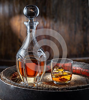 Carafe of whisky and glass of whisky on old wooden cask at the dark background