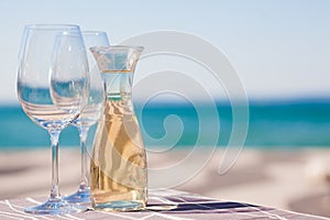 The carafe of white wine and a glass of wine by Garda Lake beach