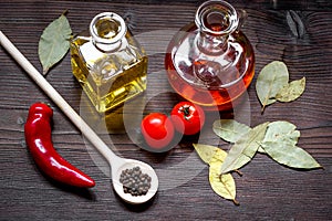 Carafes with oil and tomatoes on wooden background