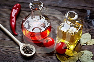 Carafes with oil and tomatoes on wooden background