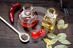 Carafes with oil and tomatoes on wooden background