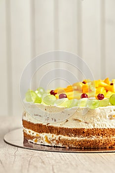 Caramel cake with fruits. Board with delicious tasty homemade cake on table. Wooden background