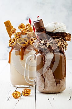 Caramel and chocolate crazy freakshake milkshakes with brezel waffles, popcorn, marshmallow, ice cream and whipped cream.