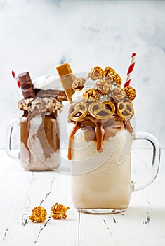 Caramel and chocolate crazy freakshake milkshakes with brezel waffles, popcorn, marshmallow, ice cream and whipped cream.