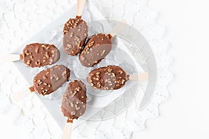 Caramel and chocolate nut covered ice cream sticks on ice