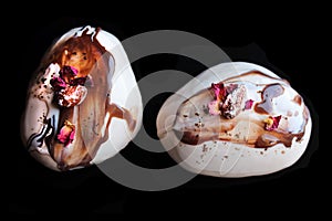 Caramel, coffee and chocolate stone desserts with almonds and rose petals top down on black background