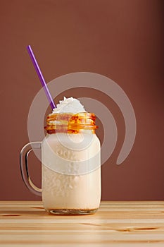 Caramel frappucino milkshake with coffee on wooden table. Salted caramel ice cream sundae. Cold coffee drink frappe frappuccino ,
