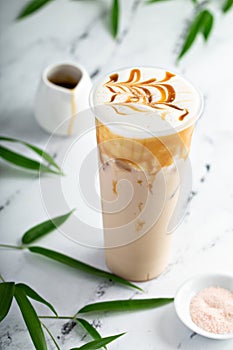 Caramel milk tea latte in a tall glass with cold foam and caramel sauce