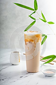 Caramel milk tea latte in a tall glass with cold foam and caramel sauce