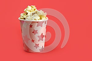 Caramel popcorn in a paper Cup on a bright red background, copy space