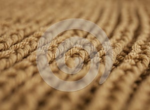 A caramel scarf, lines of the pattern, soft focus.