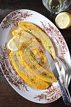 Caramelized fried bananas on vintage plate and glass of white wine