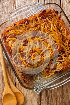 Caramelized Noodle and Pepper Yerushalmi Kugel with raisins close-up in a glass bowl. Vertical top view