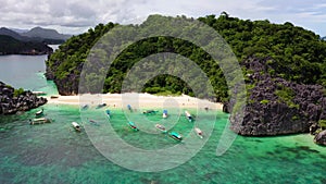 Caramoan Islands, Camarines Sur, Matukad, Philippines. Tropical island with a white sandy beach. Boats and tourists on the beach.