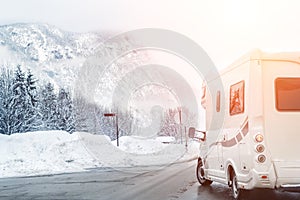 Caravan or campervan turning from road with beautiful mountain alpine landscape on background at cold winter season.Family