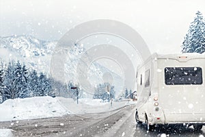 Caravan or campervan turning from road with beautiful mountain alpine landscape on background at cold winter season.Family
