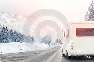 Caravan or campervan turning from road with beautiful mountain alpine landscape on background at cold winter season.Family