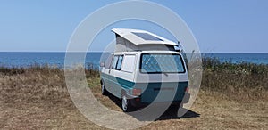 Caravan car solar panels electricity  by the sea in summer beach trees blue sky  travel