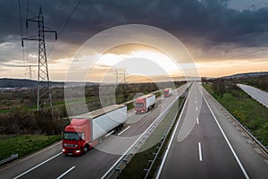 Caravan or convoy of Red trucks on highway photo