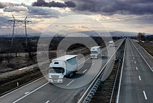 Caravan or convoy white lorry trucks on country highway