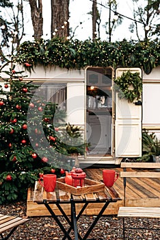 Caravan mobile home with terrace, Mobile home decorated with Christmas decor. Festive atmosphere - lights, red blankets, Christmas