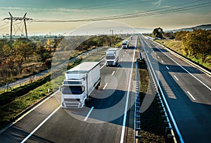 Caravan of white trucks on highway photo