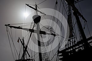 A caravel, an old sailing ship in front of the bright sun in the back light.