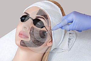 Carbon face peeling procedure in a beauty salon.
