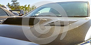 Carbon fiber hood of a silver car on a sunny day