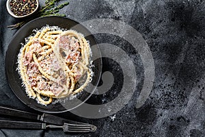 Carbonara pasta, bucatini with pancetta, egg, parmesan cheese and cream sauce. Black background. Top view. Copy space