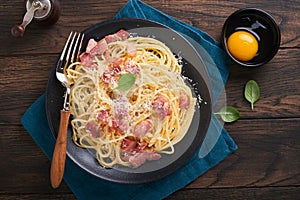 Carbonara pasta. Spaghetti with pancetta, egg, parmesan cheese and cream sauce on old dark black wooden table background.