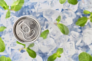 Carbonated drink in a aluminium tin can on the background of ice cubes and fresh mint leaves. Top view.