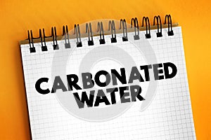 Carbonated Water is water containing dissolved carbon dioxide gas, text concept on notepad