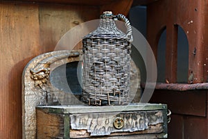 Carboy in wicker basket on wooden table