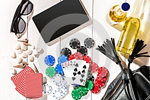 Card deck surrounded by poker chips and scattered seashells on white wooden background with copy space