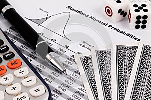 Card game, calculator, dice and pen on standard normal probabilities table.