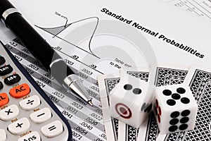 Card game, calculator, dice and pen on standard normal probabilities table.