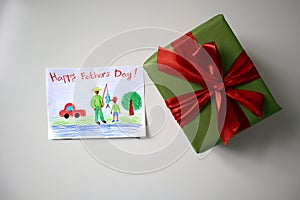 Card and gift for Father's Day. White background. The postcard is drawn by a child.