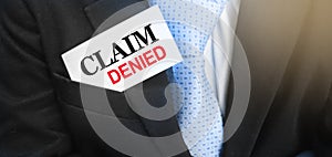 Card with text Claim Denied in the pocket of businessman wearing blue tie and a suit. Busines concept