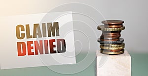 Card with text Claim Denied and stack of coins. Insurance claim rejected, business concept