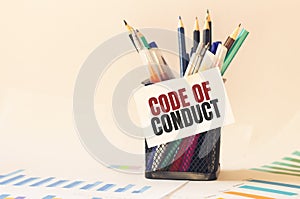 Card with text CODE OF CONDUCT on the pen box in the office. Diagram and white background